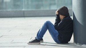 Smutny chłopiec siedzi na ulicy