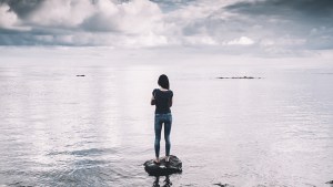Kobieta stoi na kamieniu w środku morza