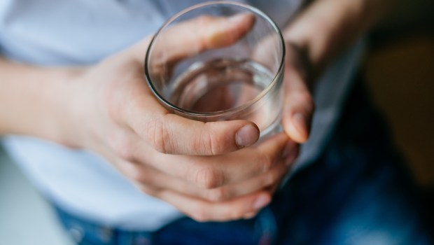 man's hand holding glass with water