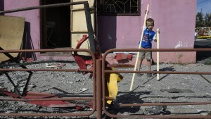 chłopiec bawi się przed swoim domem zniszczonym w nocnym bombardowaniu, Ukraina