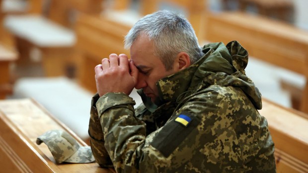 ukraiński żołnierz modli się w kościele