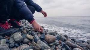chłopiec zbiera kamienie na brzegu morza
