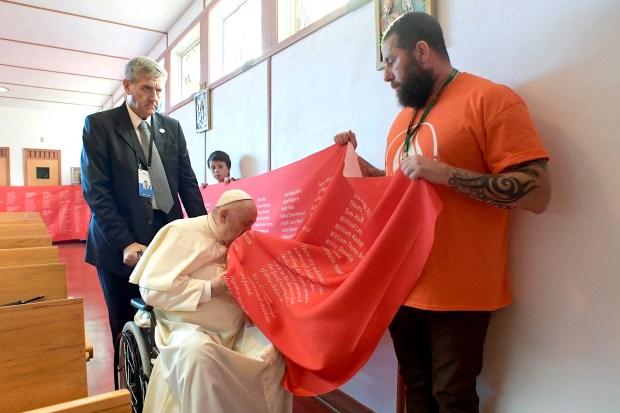 Pope Francis kissing a banner with names of victims of abuse committed at residential schools run by the Catholic Church,