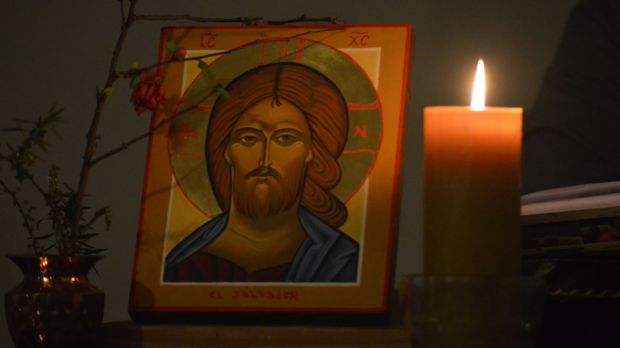 ikona Chrystusa Pantokratora przy zapalonej świeczce wieczorową porą