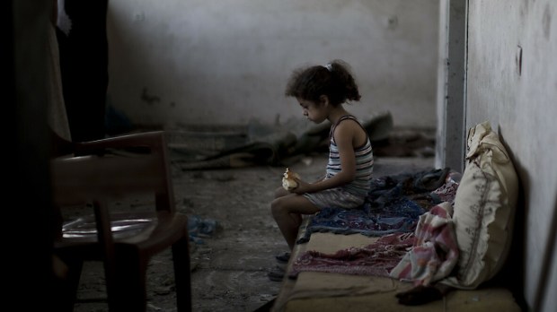 Dziewczynka z Palestyny siedzi w ruinach swojego domu, sierpień 2014 r.
