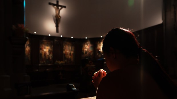 pogrążona w depresji kobieta modli się w ciemnym kościele