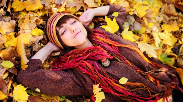 kobieta odpoczywa leżąc na jesiennych liściach