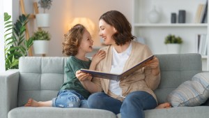 Matka i córka czytają razem bajki na kanapie