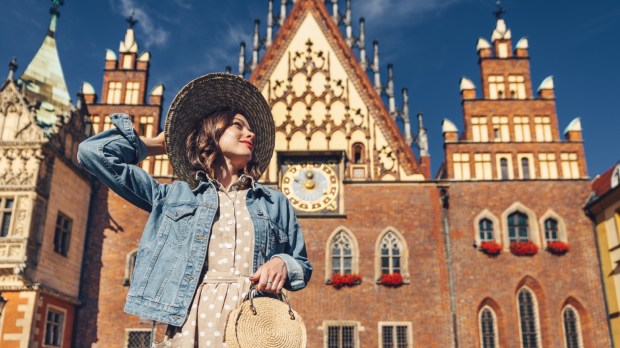 Najciekawsze polskie rynki. Młoda dziewczyna w kapeluszu stoi w słoneczny dzień na rynku we Wrocławiu.