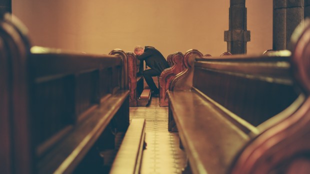 zasmucony mężczyzna siedzi w ławce w pustym kościele
