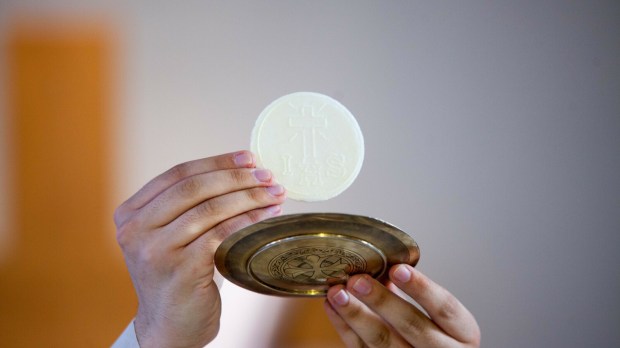 Ksiądz podnosi do góry Eucharystię