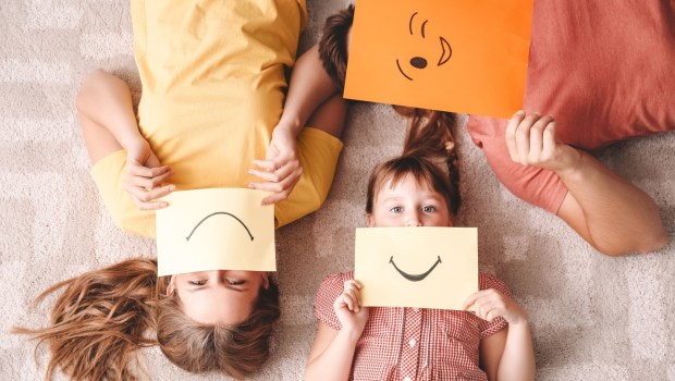mama, tata i dziecko pokazują emocje przy pomocy karteczek z emotikonami