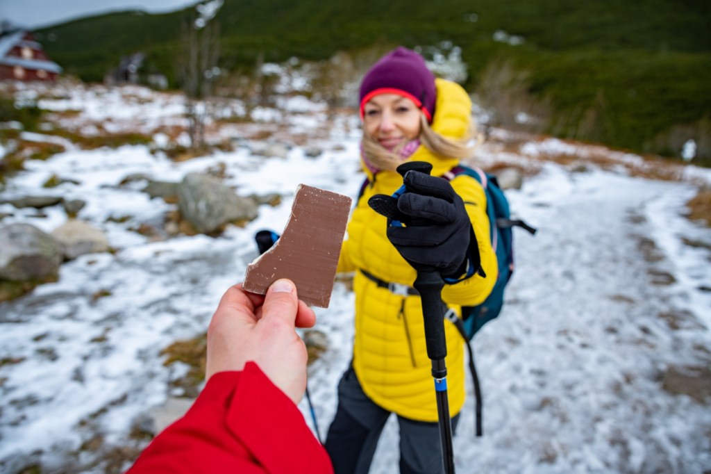 Turyści dzielą się tabliczką czekolady podczas zimowej górskiej wędrówki