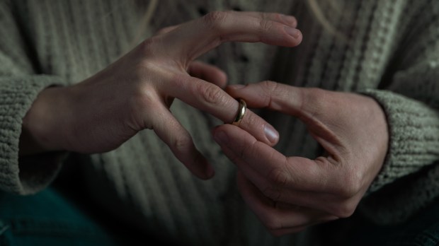 kobiece dłonie, z których jedna ściąga z palca obrączkę; kobieta rozważa złożenie pozwu do sądu kościelnego o stwierdzenie nieważności małżeństwa