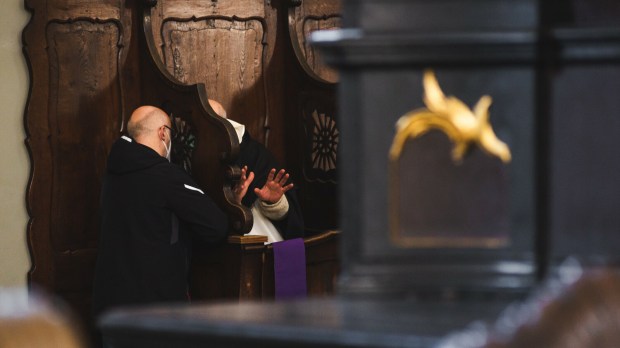 Ksiądz i penitent w konfesjonale podczas spowiedzi
