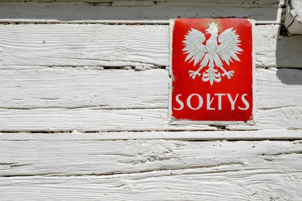 Tabliczka sołtysa na ścianie drewnianej chaty