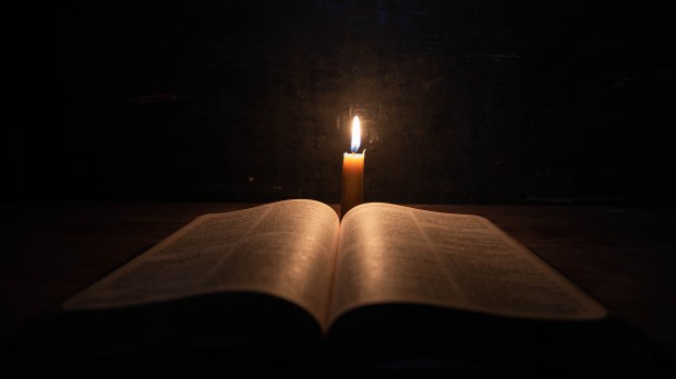 Otwarta Biblia i zapalona świeczka
