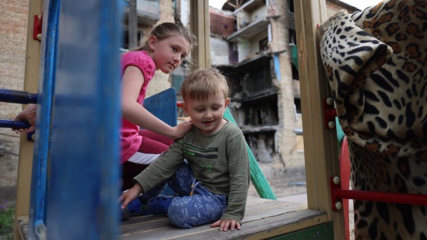 Ukraińskie dzieci bawią się przed domem zniszczonym w wyniku rosyjskiej inwazji we wsi Horenka pod Kijowem