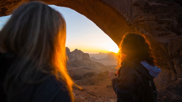 Dwie dziewczyny spoglądają na pustynny krajobraz o zachodzie słońca