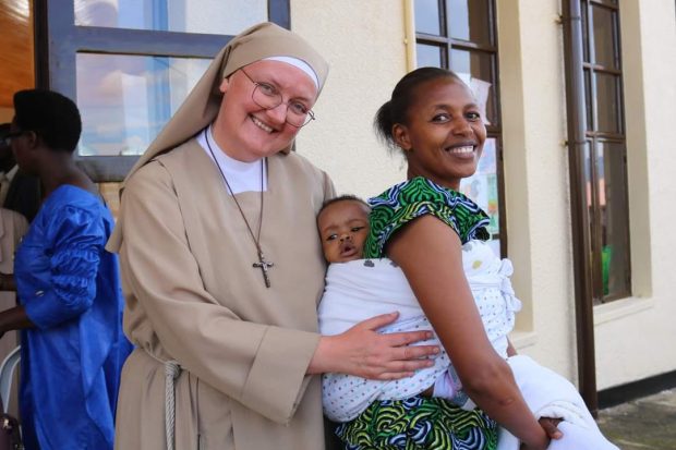 Siter Pia with a mother and child, smiling